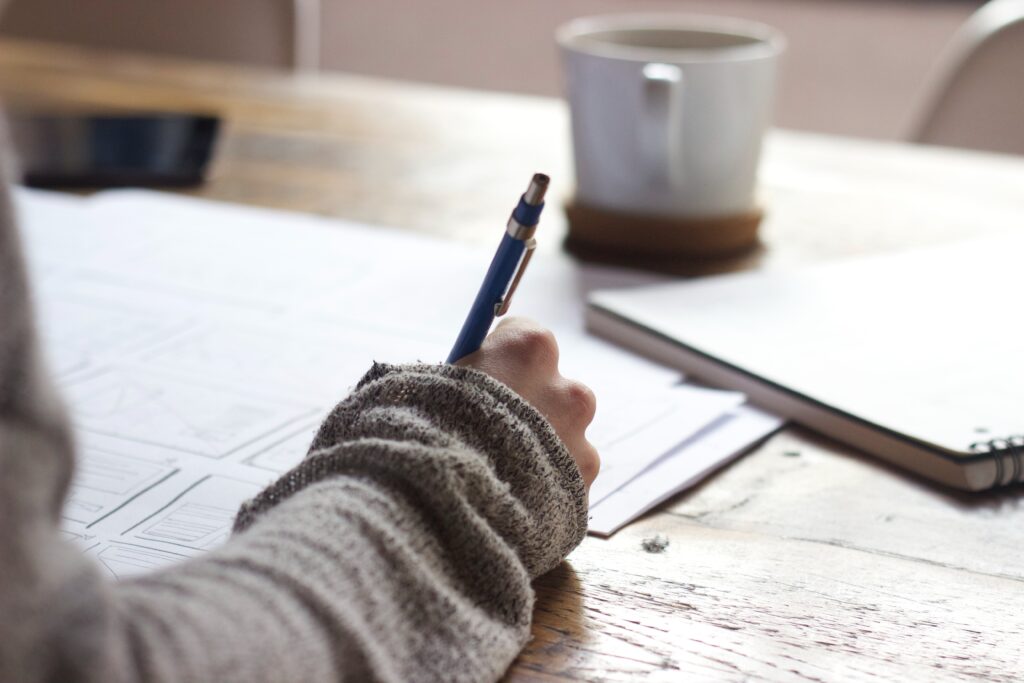 person writing on finance paperwork and documents on a table